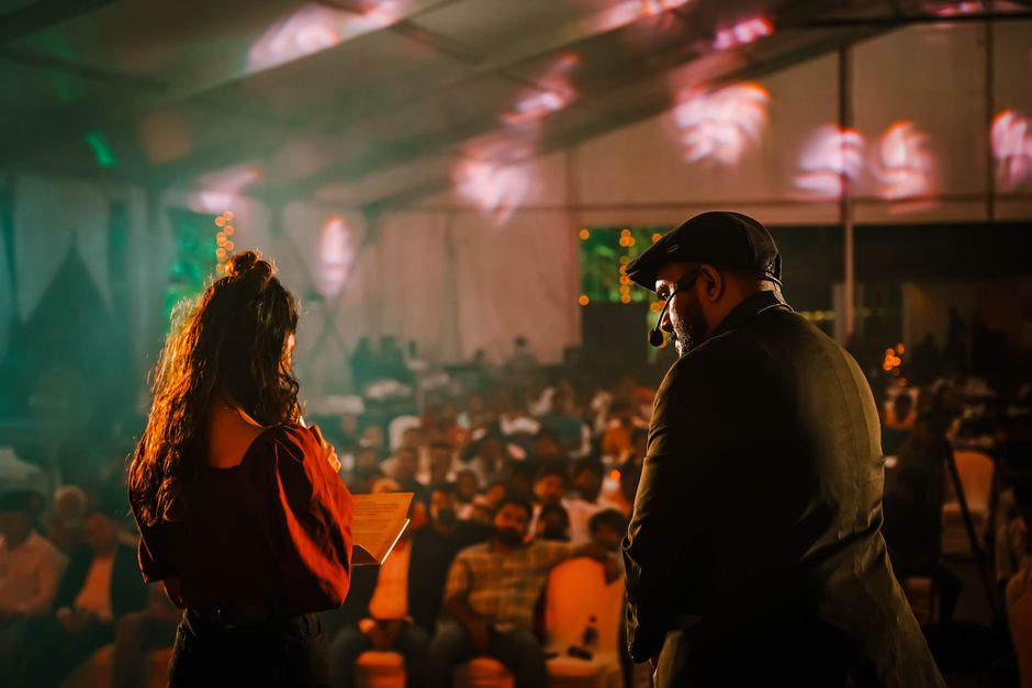 Performers engaging with an audience at a lively indoor event with colorful lighting.